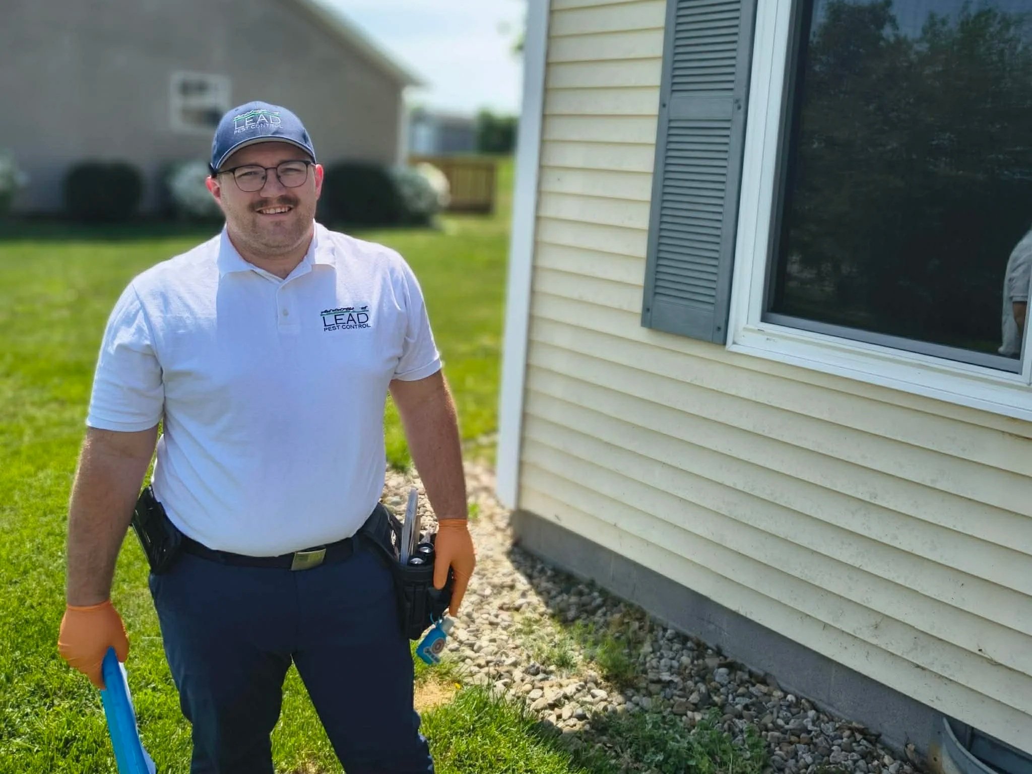 Pest control technician standing outside home after exterior service in Elizabethtown KY