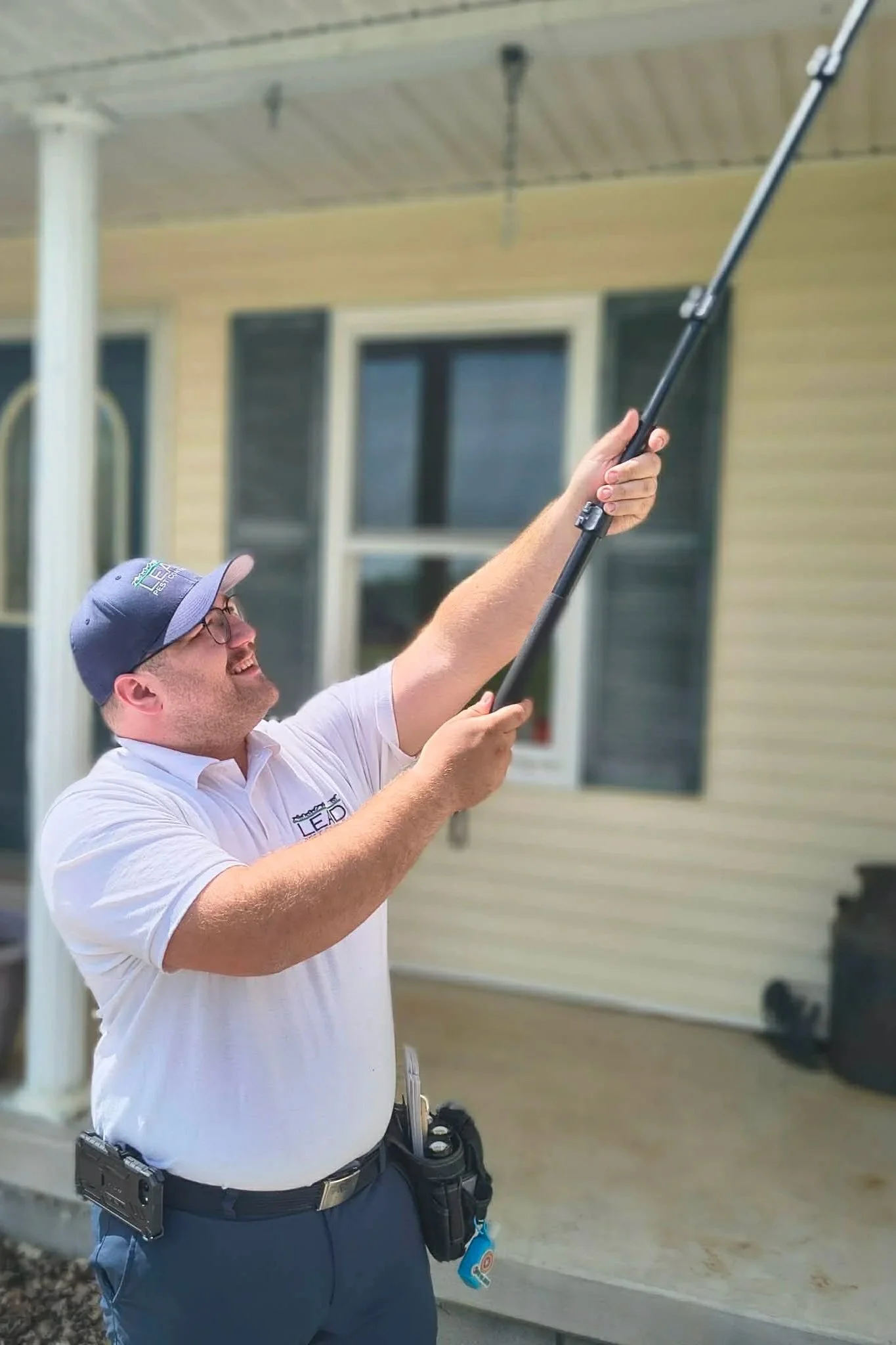 Pest control technician treating roofline and eaves of home in Elizabethtown KY