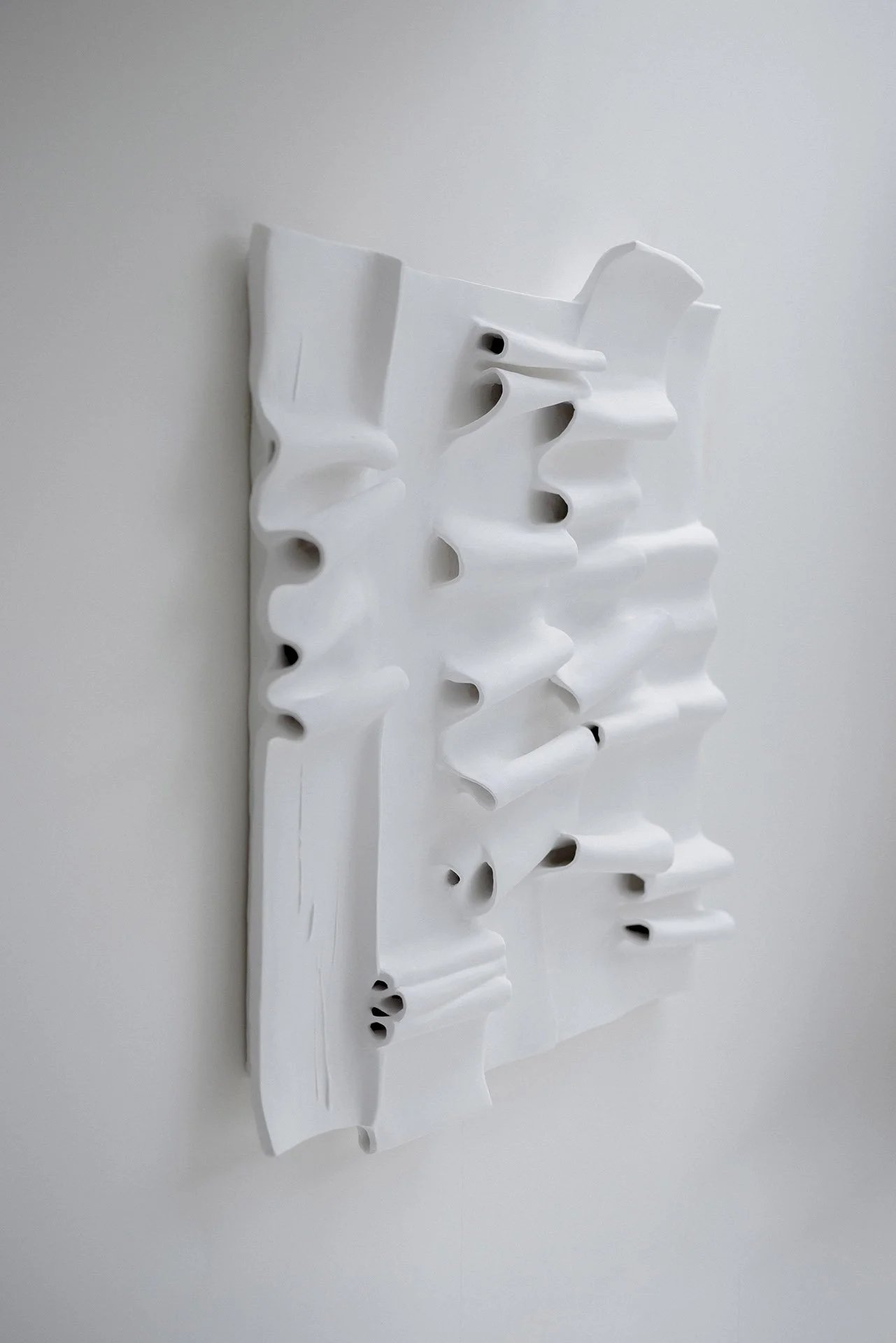 Three-quarter view of The Pulse - abstract wall sculpture with undulating white plaster forms