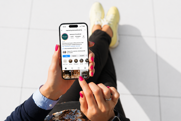Person der sidder på gulvet og bruger en smartphone med Instagram-appen.