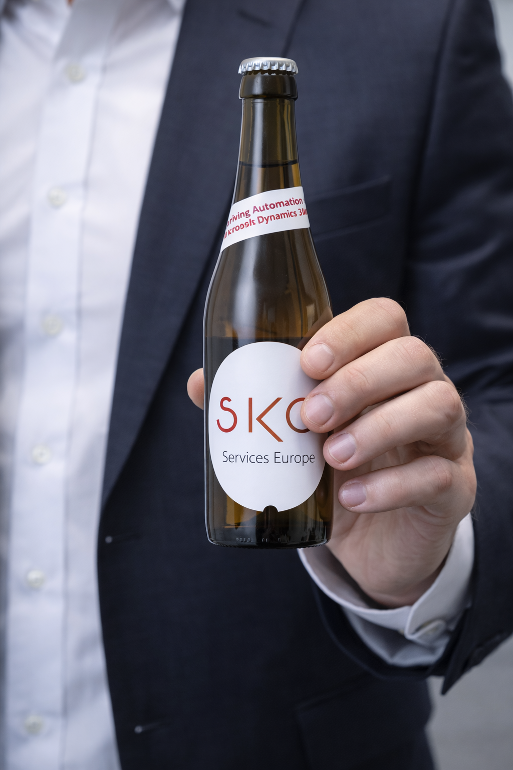 Person i habit holder en glassflaske med etiketten 'SKG Services Europe'