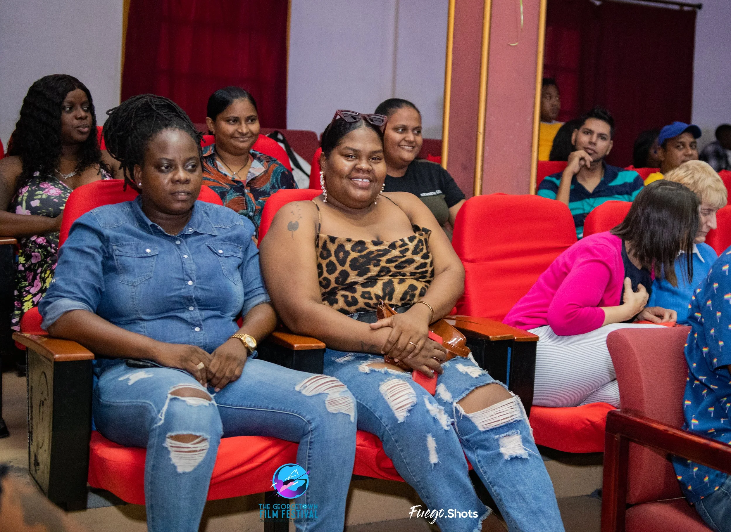 Audience seated in theater at the George Town Film Festival, with people smiling, listening, and observing.