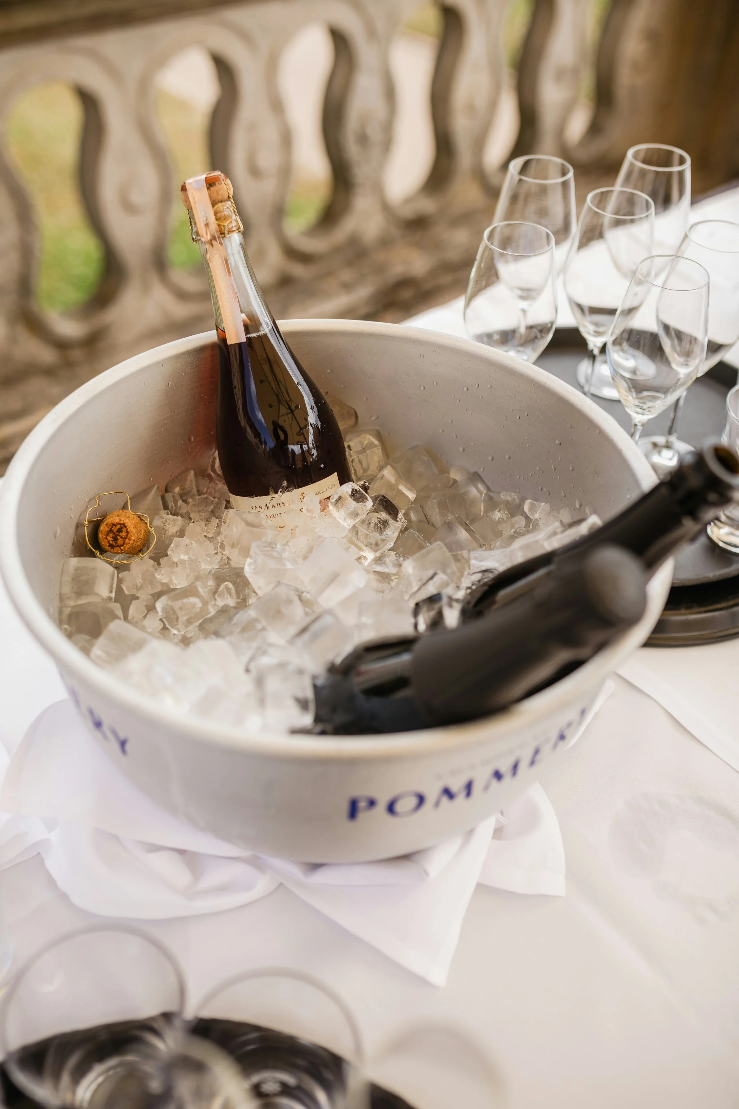 Three bottles of champagne in an ice bucket and a group of glasses.