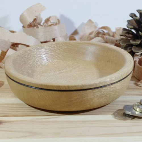 A wooden bowl on a wooden surface with pine cones and wood shavings in the background.