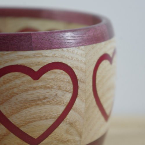 Close-up of a wooden bowl with red heart designs.