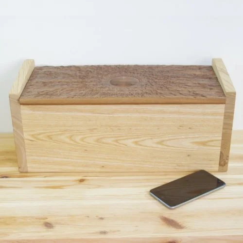 Ash Wooden box with a Walnut lid and a smartphone placed on a wooden surface in front of it.