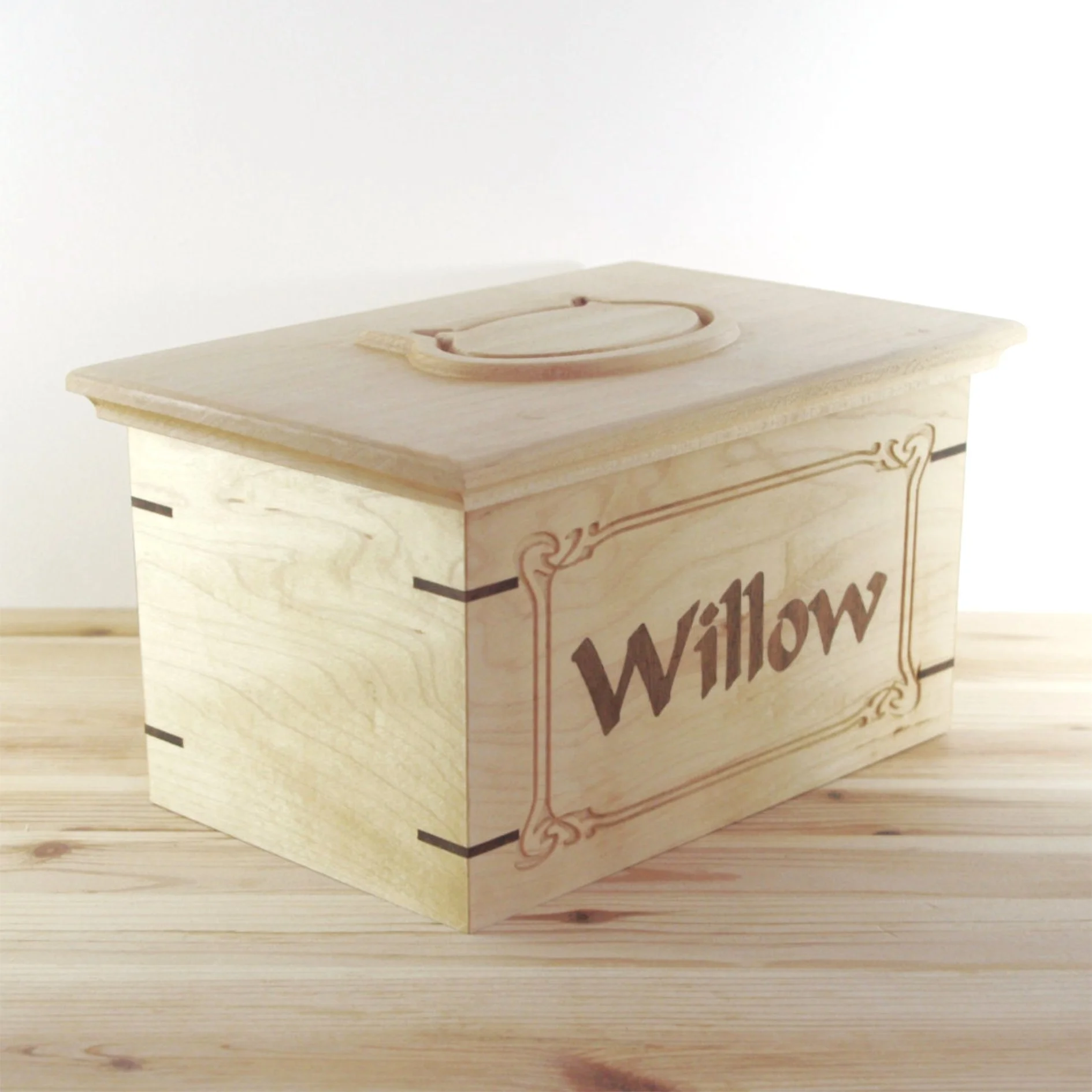 Wooden pet urn 'Willow' written on the side, placed on a wooden surface.