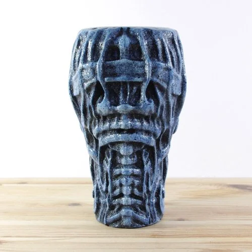 wooden skull-shaped vase with a blue and black painted surface on a wooden surface