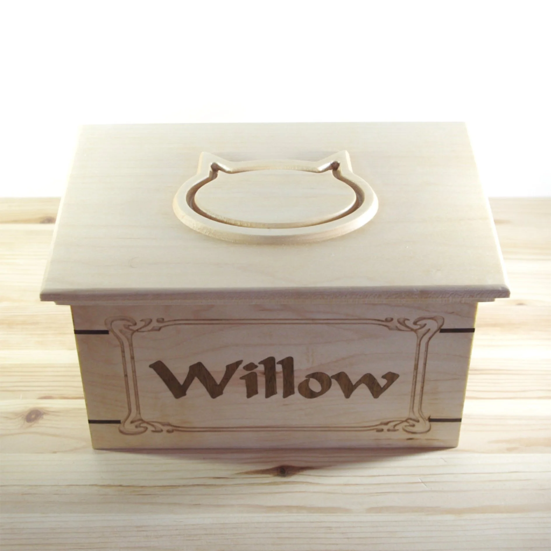 Pet urn with a carved cat outline on top and the word "Willow" engraved on the front.