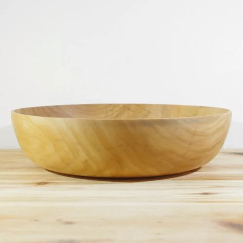 Wooden bowl on a light wooden surface against a plain white background.