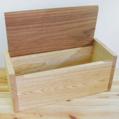 Wooden storage box with a hinged lid open, sitting on a wooden surface.