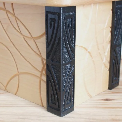 Close-up of a black decorative corner piece on a keepsake box with a textured pattern.