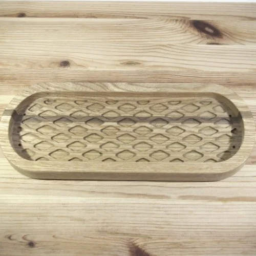 A wooden dish with a diamond design, placed on a wooden surface.