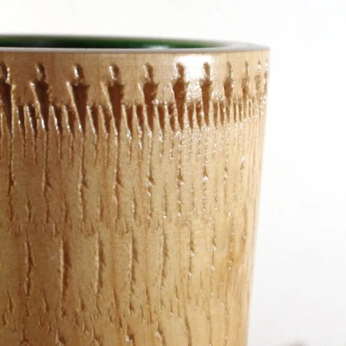 Close-up of a wooden vase with a textured, decorative pattern.