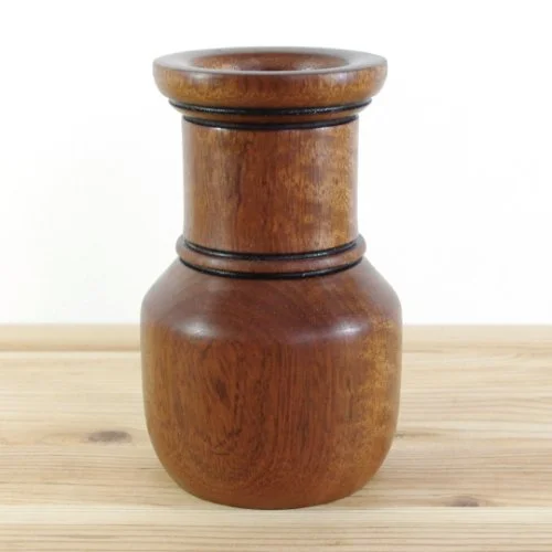 Wooden vase with a smooth, rounded shape, placed on a wooden surface.
