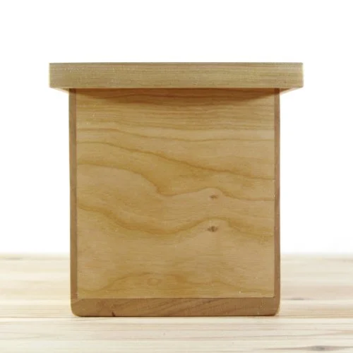A small wooden keepsake box, placed on a wooden surface, against a plain white background.