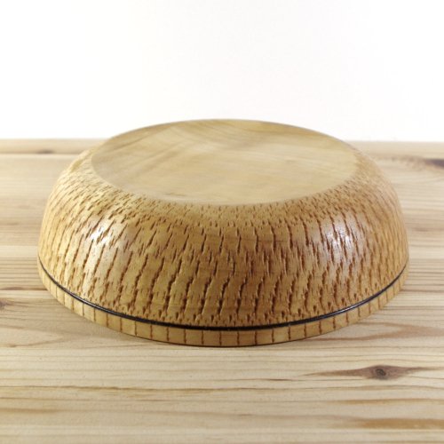 A round wooden bowl turned upside down on a wooden surface.