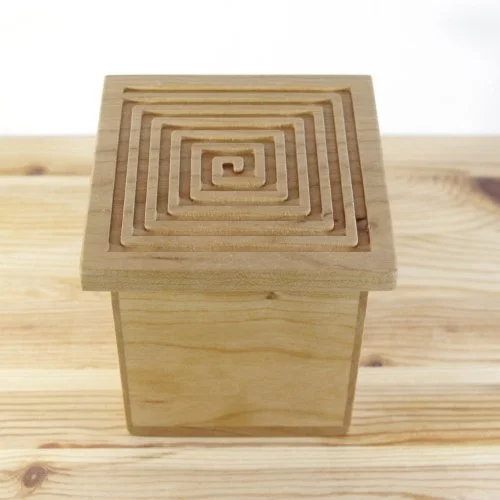 A wooden keepsake box with a square maze carved on the top surface.