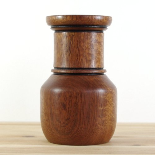 A wooden container with a rounded base and a cylindrical top, sitting on a wooden surface.