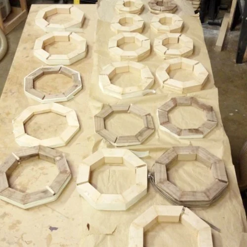 Multiple octagonal wooden frames arranged on a worktable, likely in a woodworking or craft workspace.