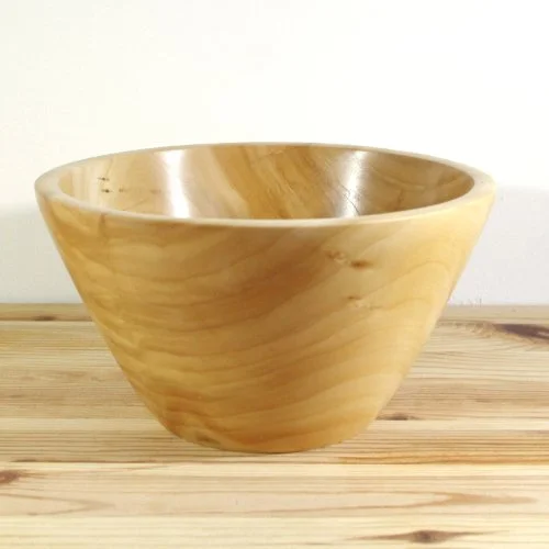 A wooden bowl on a wooden surface with a plain white background.