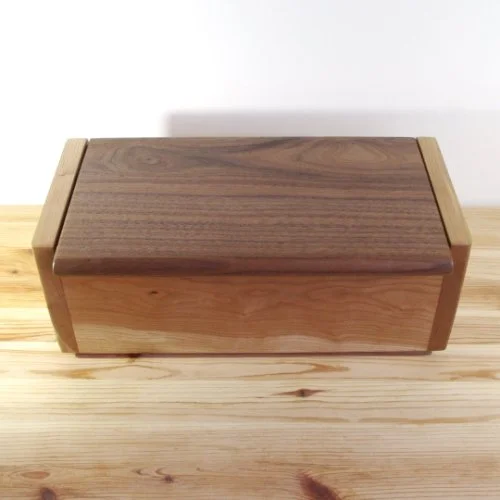 Ash wooden storage box with a Walnut lid on a light wood table.