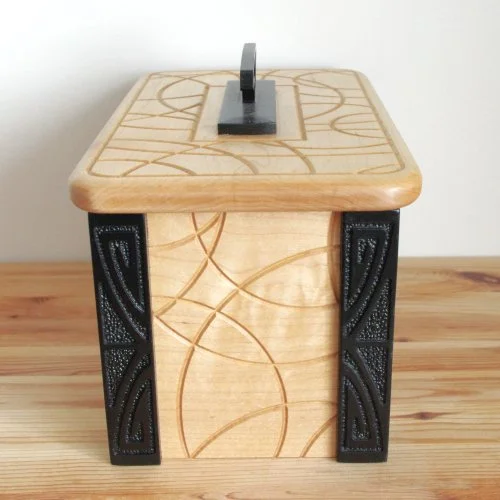 A wooden keepsake box with dark decorative legs, placed on a wooden surface.