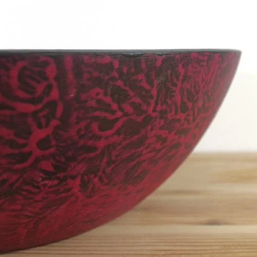 Close-up of a red and black bowl placed on a wooden surface.
