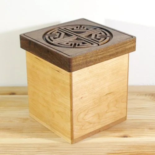 A wooden square keepsake box with a decorative carved lid.