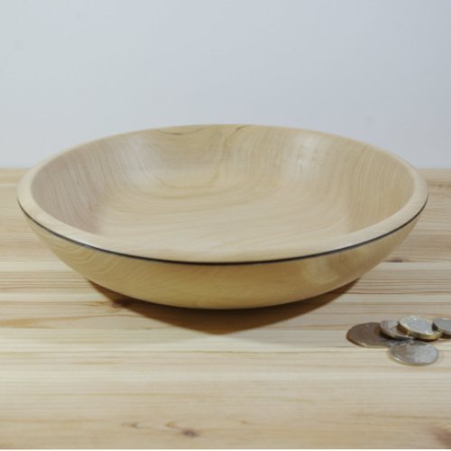A light wood bowl on a wooden surface with some coins beside it.