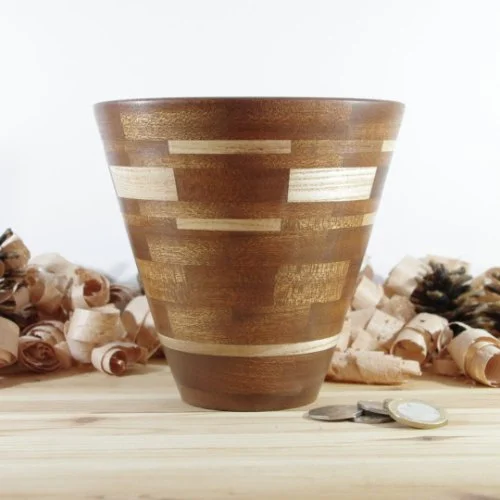 segmented wooden vase on a wooden surface, with rolled paper and coins in the background.