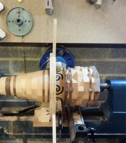 Woodturning lathe with a partially carved wooden sculpture of an owl in progress.