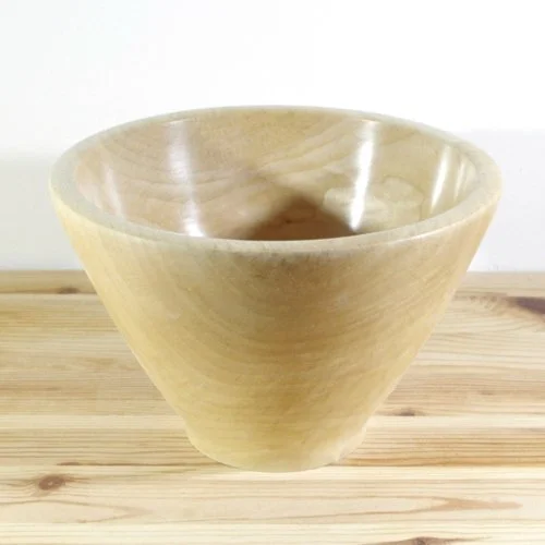 Wooden bowl on a light wooden surface against a plain white background.