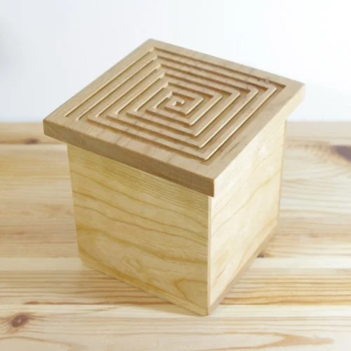Wooden keepsake box with a spiral design on top, placed on a wooden surface.