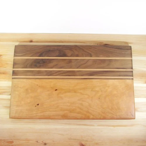 A wooden cutting board with a natural wood grain pattern placed on a light wood surface.