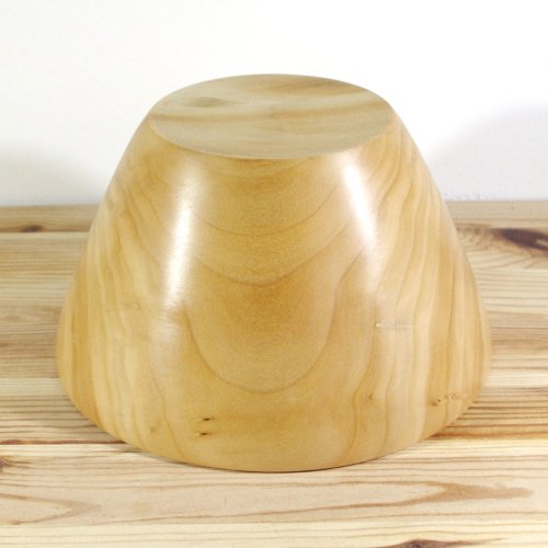 Wooden bowl on a wooden surface with a white background.