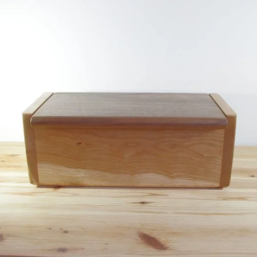 Ash wooden box with a Walnut lid, placed on a wooden surface.