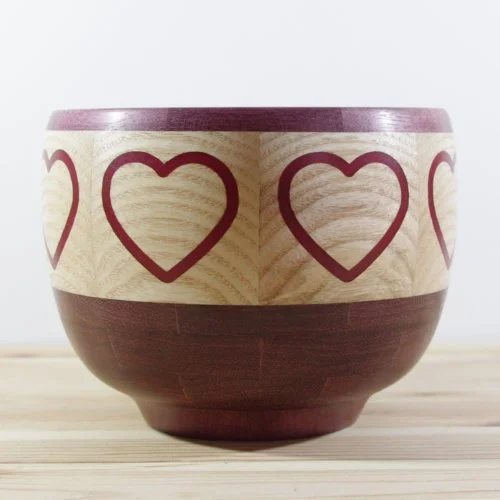 Wooden bowl with a purple heart top and bottom, decorated with epoxy hearts around the Ash wood middle section.