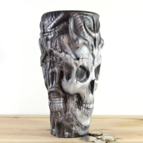 A wooden vase inspired by H.R.Giger with intricate carvings, placed on a wooden surface with some coins nearby.