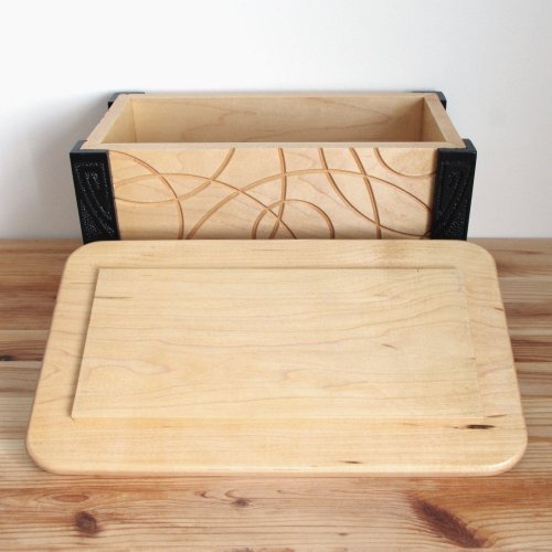 Wooden keepsake box with lid resting on table in front of it.