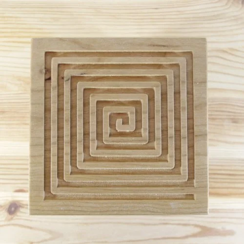 Wooden keepsake box lid with a square spiral pattern on a wooden surface.