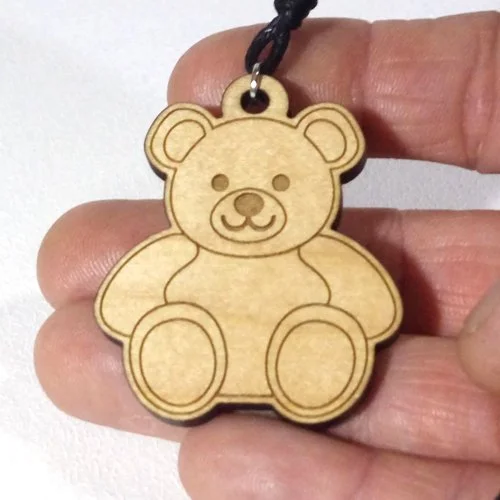 Wooden teddy bear-shaped keychain with a black string attached.