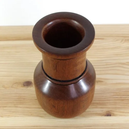 Wooden vase on a wooden surface.