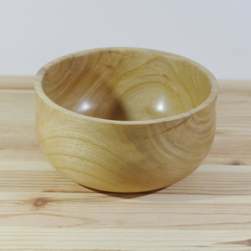 Wooden bowl on a wooden surface with a light background.