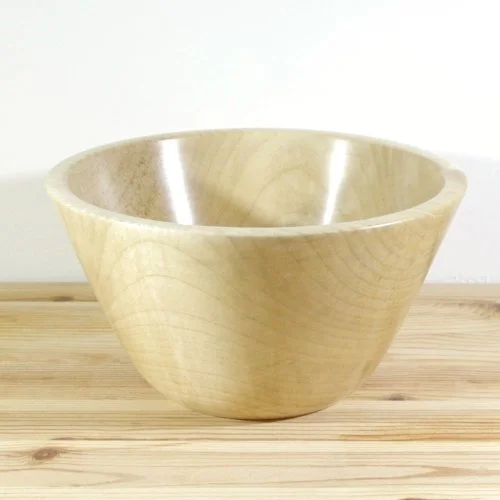 A wooden bowl on a light wooden surface against a white background.