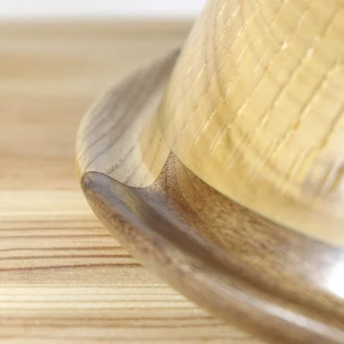 Close-up of the rim of a wooden bowl placed on a wooden surface.
