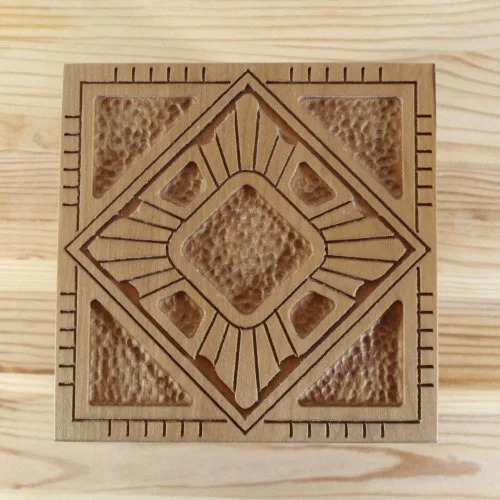 A wooden keepsake box with a carved lid, placed on a light wooden surface.