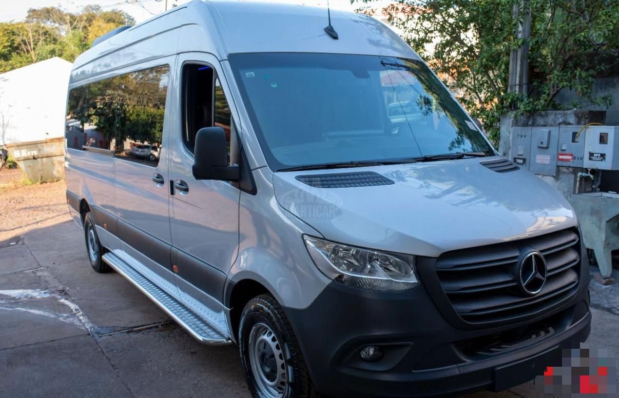 Vans Mercedes-Benz prata estacionada na rua com árvores ao fundo e caixas de distribuição elétrica ao lado.