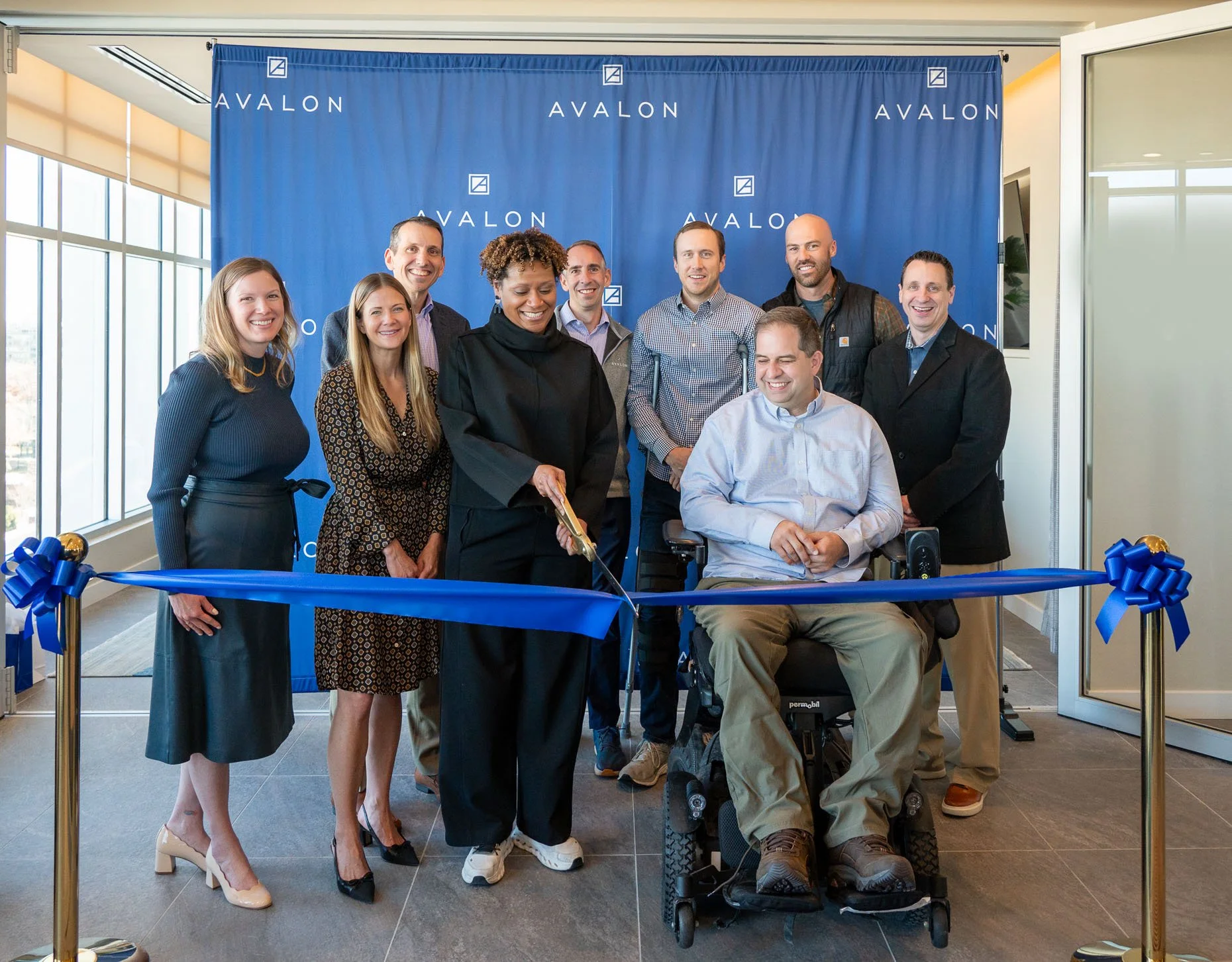 Ribbon cutting event with corporate executives in front of Avalon curtain