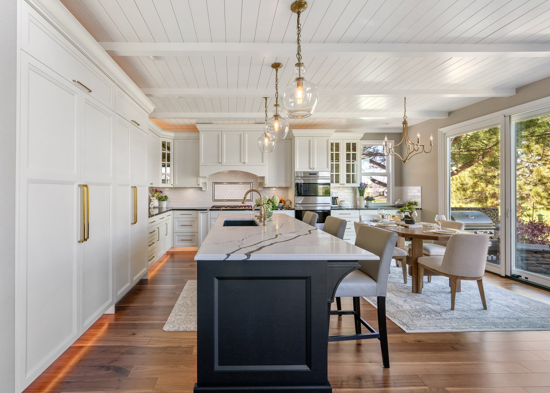 White cabinetry with black center island and marble countertop. Dine in eating area